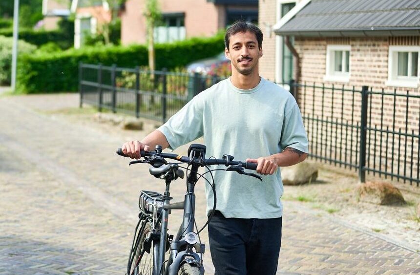 Jonge man met fiets aan de hand in een klein straatje